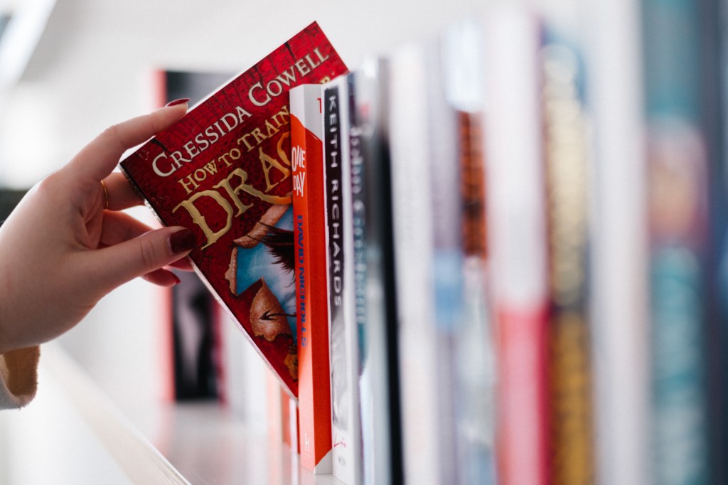 Hand grabbing a book from the bookshelf.